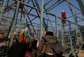 A girl sits on the top of a swing boat at an amusement park, in Douma