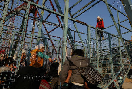 A girl sits on the top of a swing boat at an amusement park, in Douma