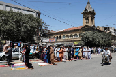 Men attend Friday prayers during the holy fasting month of Ramadan, along a road in Karachi,