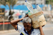 Man carries a bucket filled with water bottles on a hot day in Mumbai