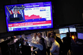 Traders work, as a screen broadcasts a news conference by U.S. Federal Reserve Chair Jerome Powell following the Fed rate announcement, on the floor of the NYSE in New York