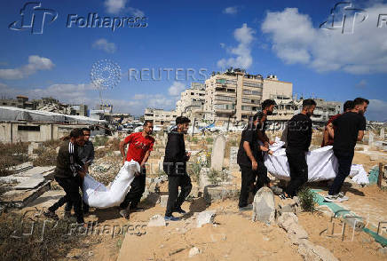 Mourners carry the bodies of members of the Al-Arabeed family killed in Israeli strikes, at a cemetery, in Gaza City