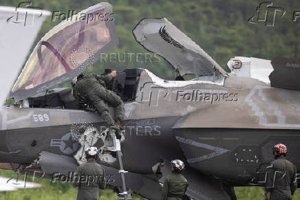 A U.S. Marine Corps pilot climbs out of an F-35 fighter jet as ground crew members assist after the plane landed at the former Roosevelt Roads military base in Ceiba