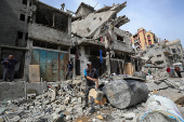 Palestinians inspect the site of an Israeli strike on a house, in Gaza City