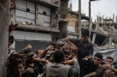 Displaced Palestinians collect donated food in Jabalia, northern Gaza