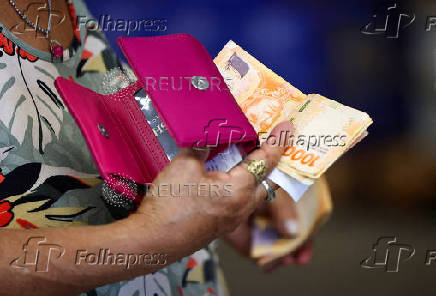 FILE PHOTO: A customer counts Argentine peso bills before checking out in a supermarket, in Buenos Aires