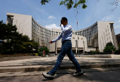 Person walks past the headquarters of the People's Bank of China, in Beijing