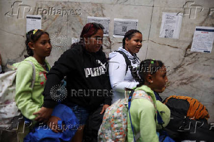 Migrants gather outside the Venezuelan embasssy waiting for a flight back to their country