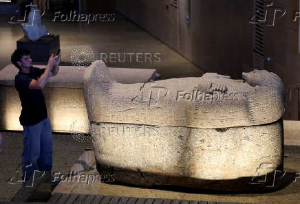 A visitor takes a photo of a museum exhibit displayed at the Grand Egyptian Museum