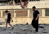 People walk at a damaged site in the aftermath of Israeli strikes, in Beirut's southern suburbs