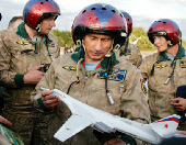 FILE PHOTO: Russian President Vladimir Putin looks at a model of the Tupolev TU-160 bomber..
