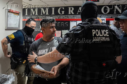 A migrant is detained by federal immigration officers at U.S. immigration court