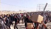 Palestinians walk back carrying aid boxes, in Rafah