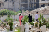 People visit the graves of their relatives at a cemetery, on the first day of the Muslim holiday of Eid al-Adha, in Damascus