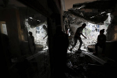 Palestinians inspect the site of an Israeli strike on a house, in Gaza City