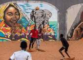 Men play soccer near a graffiti mural in Yoff, neighborhood of Dakar