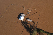 A drone view shows a boat approaching a flooded shed at a stud farm in Heatherbrae