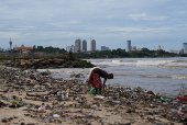 FILE PHOTO: A woman searches for recyclable items along a beach filled with discarded plastics and other materials in Colombo