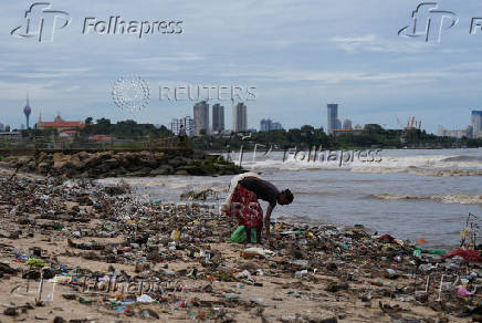 FILE PHOTO: A woman searches for recyclable items along a beach filled with discarded plastics and other materials in Colombo