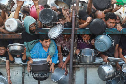 Palestinians wait to receive food from a charity kitchen, amid a hunger crisis, in Gaza City