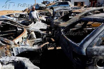 A Palestinian man inspects burnt cars, after Israeli settlers set fire to cars in the Palestinian town of Burqa