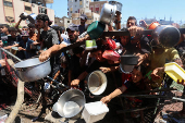Palestinians gather to receive food from a charity kitchen, amid a hunger crisis, in Nuseirat