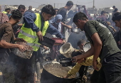 Displaced Palestinians collect donated food in Jabalia, northern Gaza
