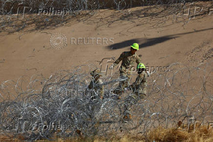 Members of the U.S. military replace concertina wire at on the U.S.-Mexico border, as seen from Ciudad Juarez