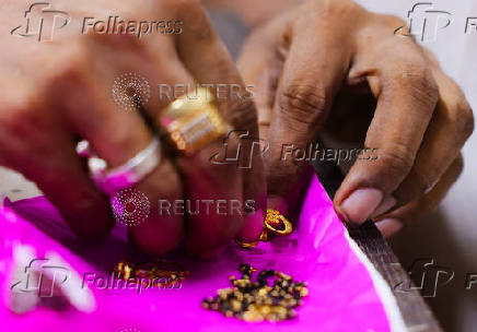 A goldsmith places gold ornaments on a paper inside a jewellery making workshop in Mumbai
