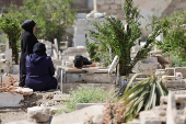 People visit the graves of their relatives at a cemetery, on the first day of the Muslim holiday of Eid al-Adha, in Damascus