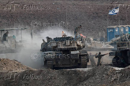 Israeli soldiers direct a tank near the Israel-Gaza border
