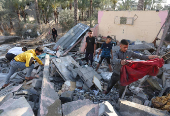 Palestinians inspect the damage at the site of an Israeli strike on a house, in Deir Al-Balah in the central Gaza Strip