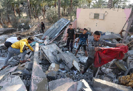 Palestinians inspect the damage at the site of an Israeli strike on a house, in Deir Al-Balah in the central Gaza Strip