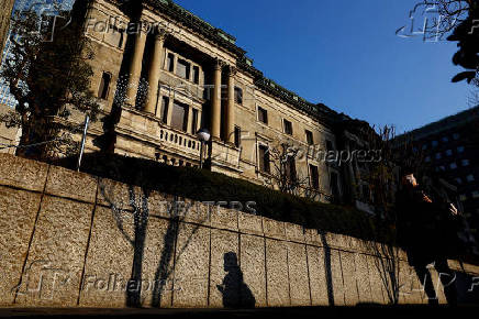 FILE PHOTO: A passerby walks past in front of the Bank of Japan headquarters in Tokyo