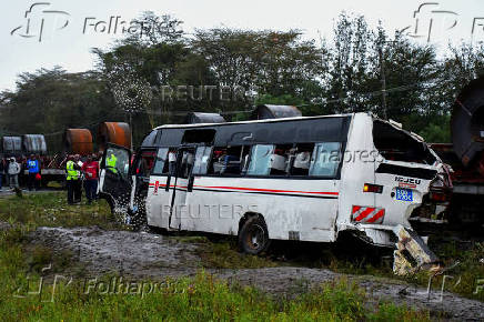 People gather in front of the wreckage of a staff bus that collided at a railway crossing in Naivasha