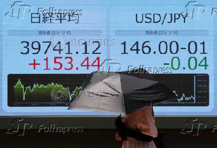 A woman holding a sunshade walks in front of a screen displaying Japan's Nikkei share average and exchange rate between Japanese yen and U.S. dollar outside a brokerage in Tokyo