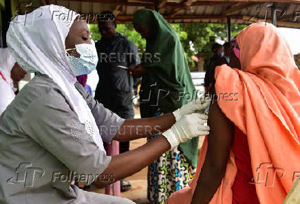 A Nigerian health official administer a mpox vaccination to a woman in Nigeria