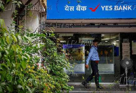 FILE PHOTO: A private security guard stands outside a branch of Yes Bank in New Delhi