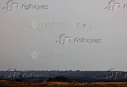 Aid packages dropped from an airplane descend over Gaza Strip, as seen from Israel