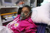 A Palestinian girl breathes through an oxygen mask inside an ambulance in Amman
