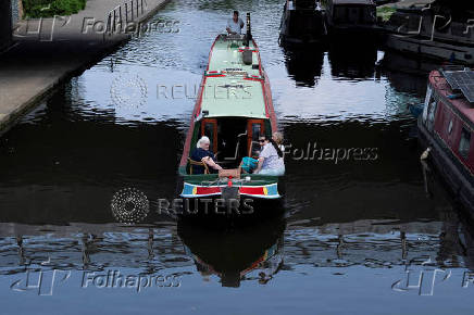 People enjoy the weather on a boat through Regent?s Canal in London