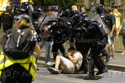 Serbian police detain a demonstrator during standoff between ruling party supporters and anti-government protesters in Belgrade