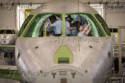 Eletricistas trabalham no jato Praetor em hangar de São José dos Campos