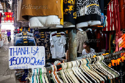 A vendor sits at her stall inside a market, in Dong Dang township