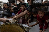 Displaced Palestinians collect donated food in Jabalia, northern Gaza