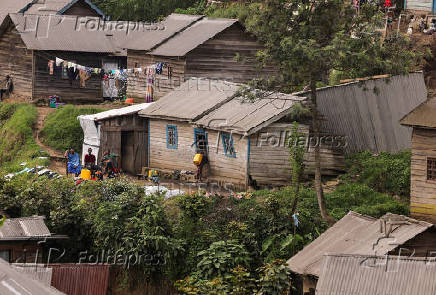 FILE PHOTO: A woman carrying a jerry can filled with water walks into her house in Mushaki