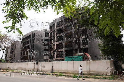 A plain clothed policeman passes by damaged buildings, where an Air India Boeing 787-8 Dreamliner plane crashed during takeoff from a nearby airport, in Ahmedabad