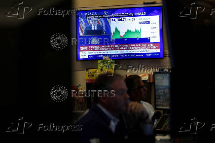 Traders work, as a screen broadcasts a press conference by U.S. Federal Reserve Chair Jerome Powell following the Fed rate announcement, on the floor of the NYSE in New York
