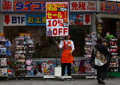 A store staff member tries to attract customers outside a store in Tokyo