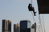 A worker paints the facade of a building in Singapore